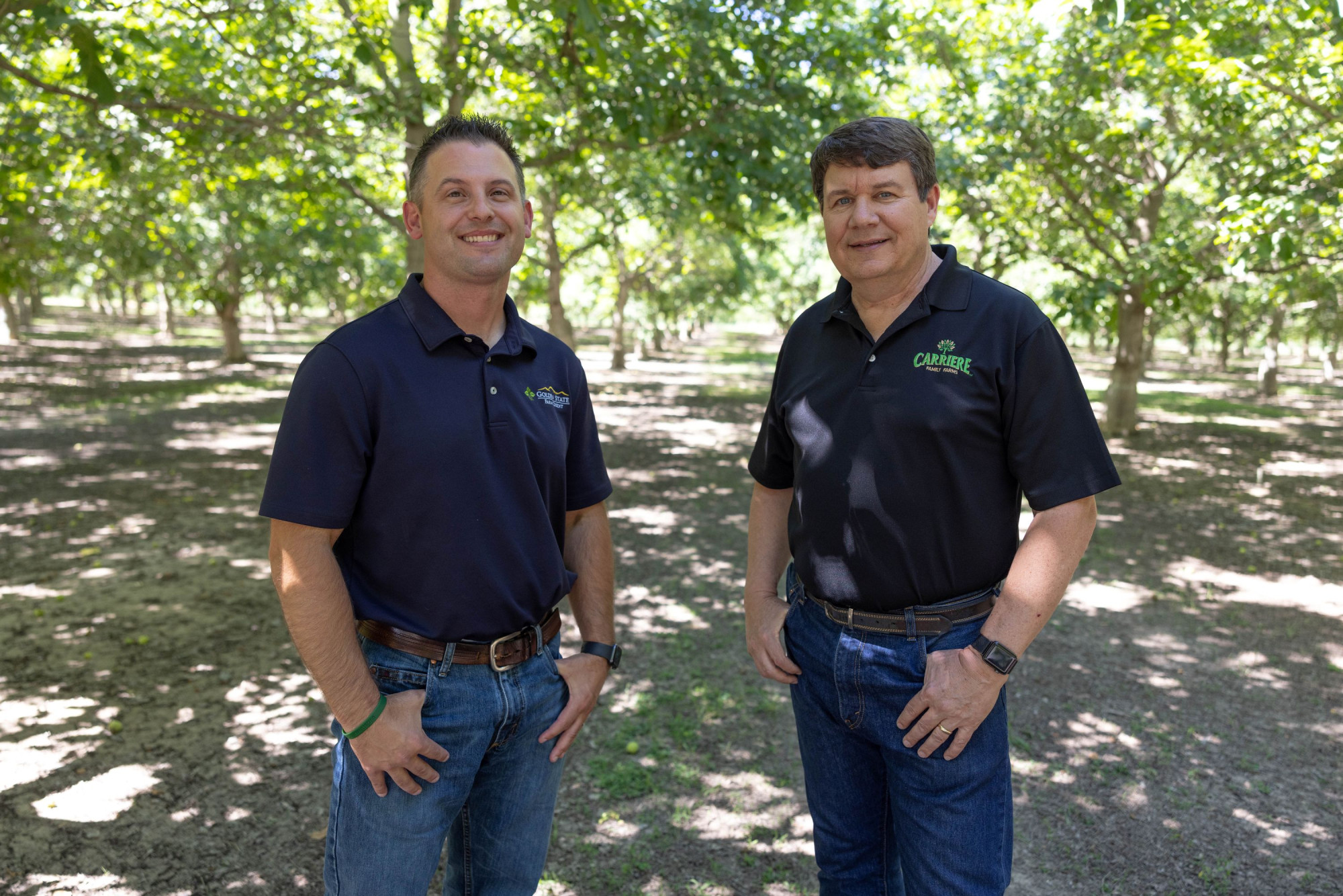 Two men shaking hands in between rows of solar panels. 